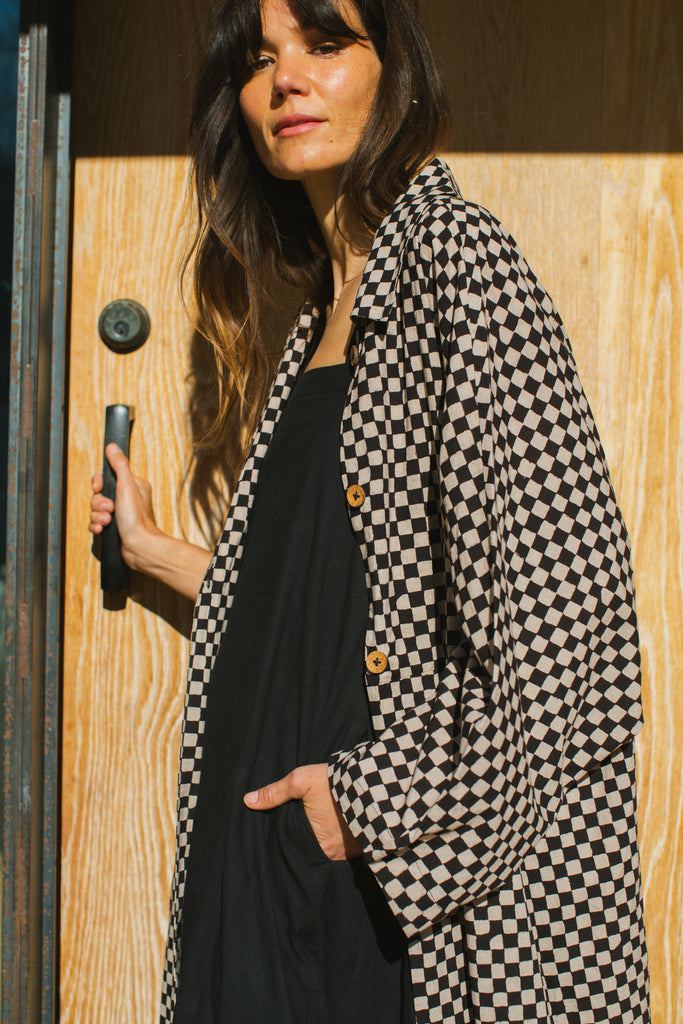Elevate your style with this eye-catching red duster jacket, adorned with coconut buttons for a touch of natural charm. Crafted from high-quality block print fabric, this jacket boasts a timeless black and white checkered pattern, adding sophistication to any ensemble