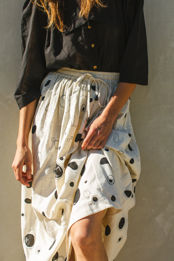 This Raindrops skirt is meticulously crafted from hand-woven fabric. Its exquisite appliqué work adds a touch of enchantment, elevating any ensemble. With its timeless black and white palette, this skirt effortlessly complements a variety of tops and shirts, ensuring versatility and sophistication with every wear.