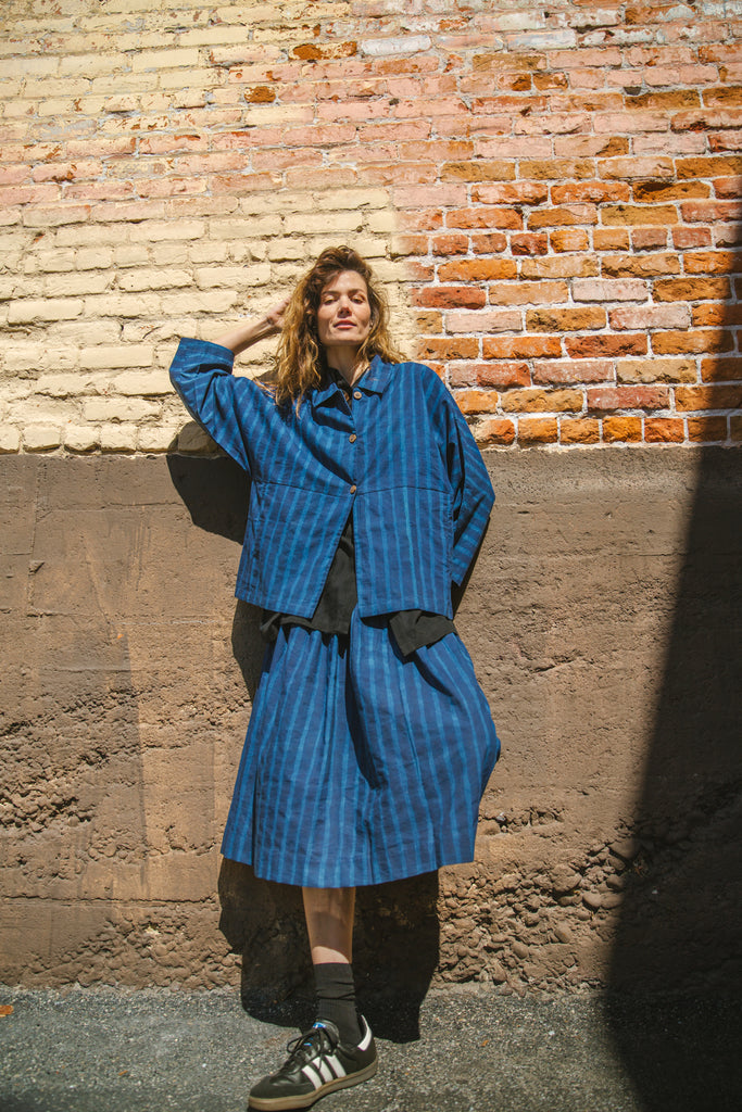 Blue striped button-up shirt with a relaxed, oversized fit, wide sleeves, a pointed collar, and a slightly structured silhouette, blending a casual and contemporary aesthetic.