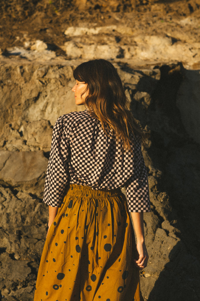 A black and white checkered blouse with a Victorian collar paired with a yellow skirt, showcasing vintage elegance.