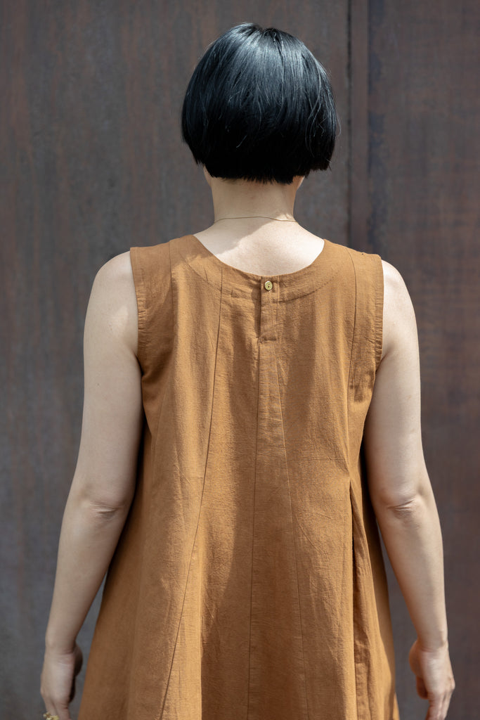 Sleeveless caramel-brown A-line midi dress with a high, round neckline. Features a voluminous flared silhouette, creating a breezy and effortless look. Made from textured, lightweight fabric for a natural, flowy drape.