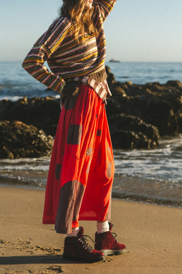 A bold red skirt with brown accents, showcasing unique appliqué craftsmanship and a versatile mid-calf length.