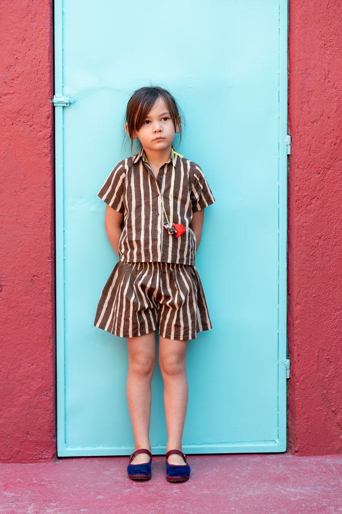 A short-sleeved, brown-and-white striped button-up shirt with a structured collar. The shirt has a relaxed fit and a slightly cropped length, giving it a casual and comfortable look. Made from lightweight fabric, it pairs seamlessly with matching striped shorts for a coordinated outfit.