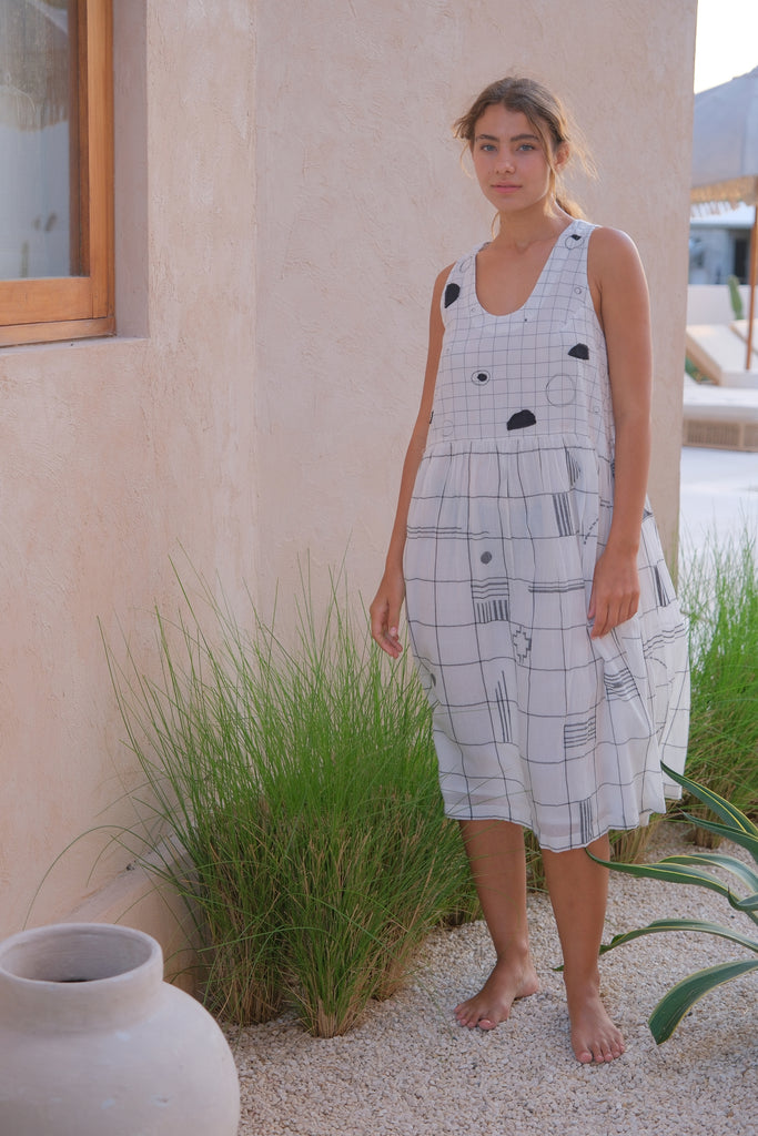 Introducing the Joan Dress, a collaboration between Audrey E Leary and World of Crow. This black and white midi-length dress features a refined mosaic pattern, a round V-neck, and is crafted from soft, handwoven cotton. Sustainably made with a relaxed fit and midweight fabric, it’s perfect for layering with the Artist Smock for a versatile look