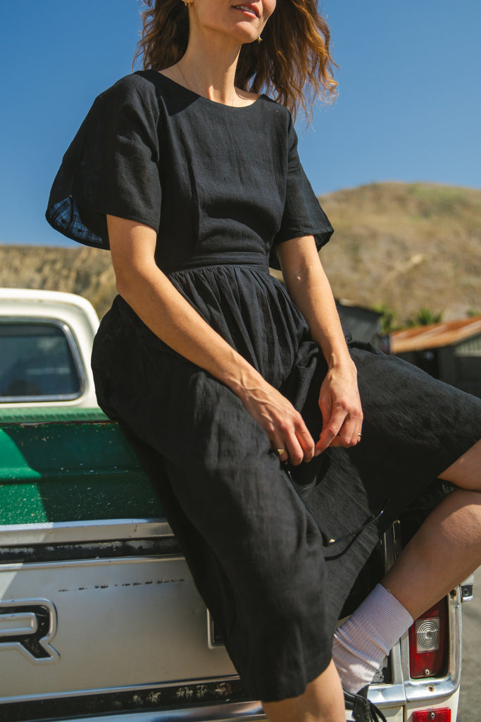 Black jamdani fabric dress with a soft, breathable texture, featuring a fitted bodice, cinched waist, and a flowy midi skirt for an effortlessly elegant and timeless silhouette.