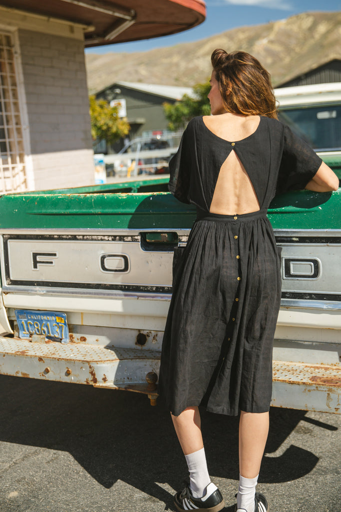 Black jamdani fabric dress with a soft, breathable texture, featuring a fitted bodice, cinched waist, and a flowy midi skirt for an effortlessly elegant and timeless silhouette.