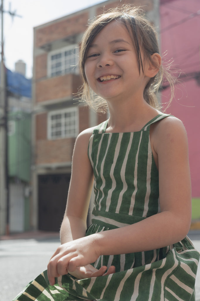 Green and white striped sleeveless dress with a halter neckline, gathered waist, and a relaxed fit.