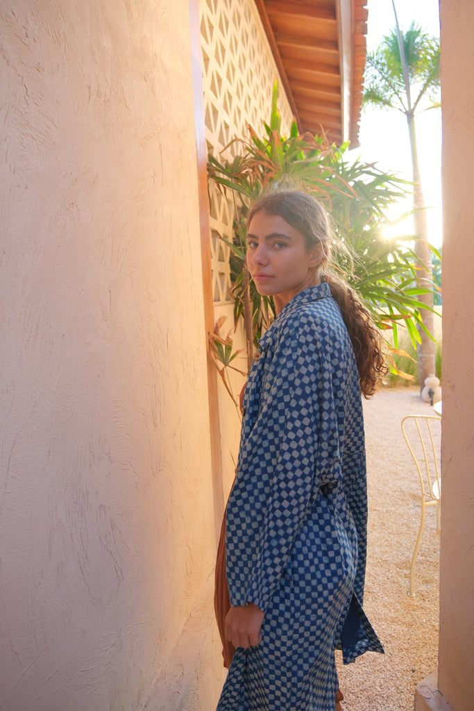 Introducing our Indigo Checkered Duster Jacket, a versatile wardrobe staple made from handwoven cotton. Featuring a classic indigo and white checkered block print, this jacket combines style and comfort effortlessly. With a straight collar, coconut buttons, and a relaxed fit, it’s perfect for layering over both dressy and casual outfits.