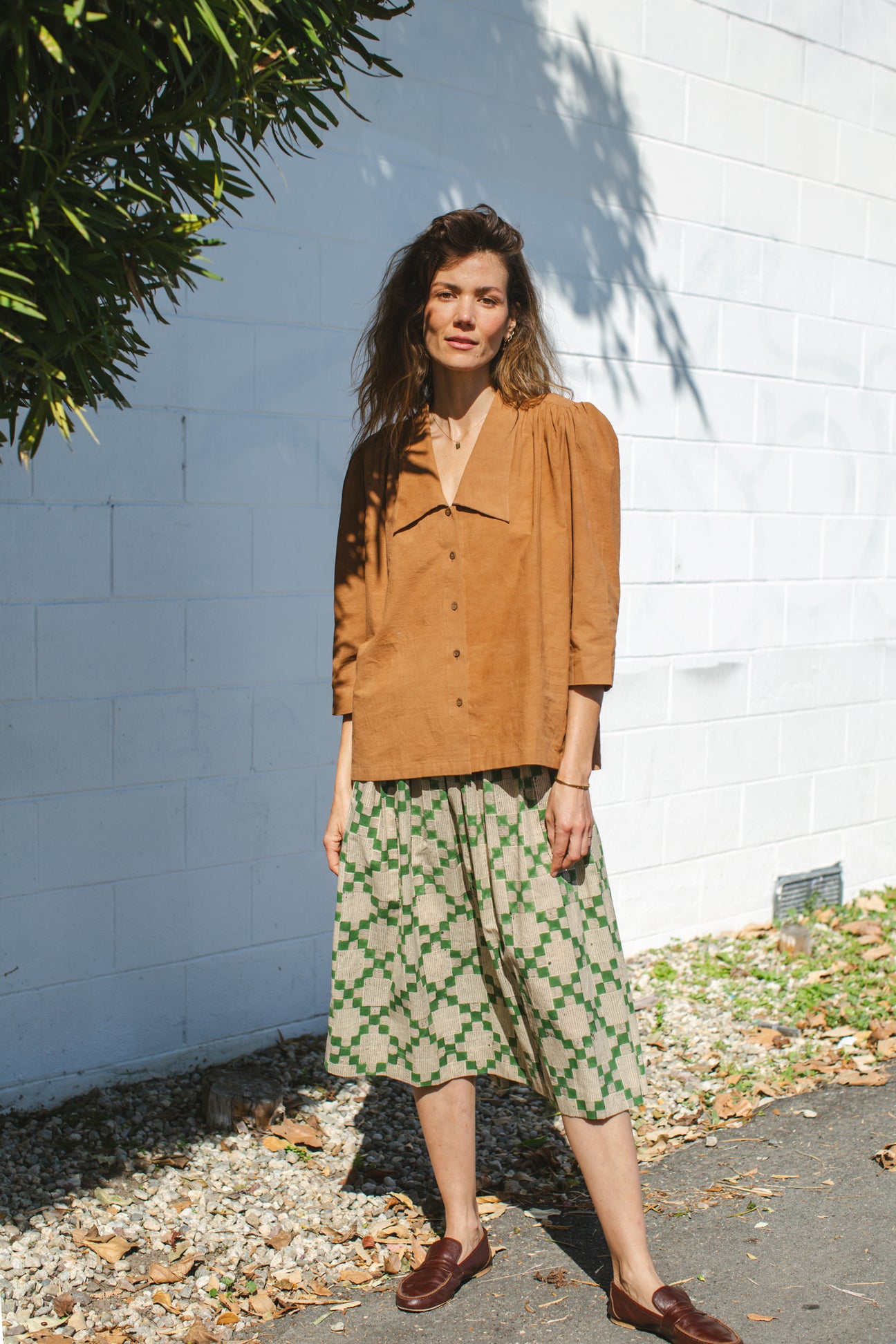 Vintage-inspired brown suede blouse with a wide-notch collar and gathered shoulders, adding a touch of retro elegance. The earthy caramel hue enhances its timeless appeal, making it a versatile statement piece.
