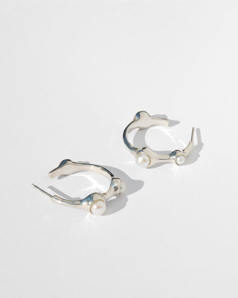 Introducing our elegant silver hoop earrings, featuring a sophisticated asymmetrical design with white pearls in varying sizes—3 mm, 4 mm, and 5 mm. Handcrafted with precision, these earrings are adorned with sterling silver posts and backs. Each pair is made to order and ships in 2-4 weeks, ensuring a unique addition to your collection.