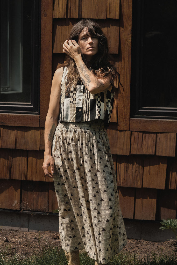Sleeveless black and ivory patchwork top made from 100% organic cotton, featuring hand block-printed geometric patterns. Ethically crafted with a mix of stripes, checks, and textured prints using azo-free dyes. Lightweight, breathable fabric with a structured yet comfortable fit—perfect for summer styling or layering. Each piece is unique, showcasing subtle variations in print and color due to its handcrafted nature.