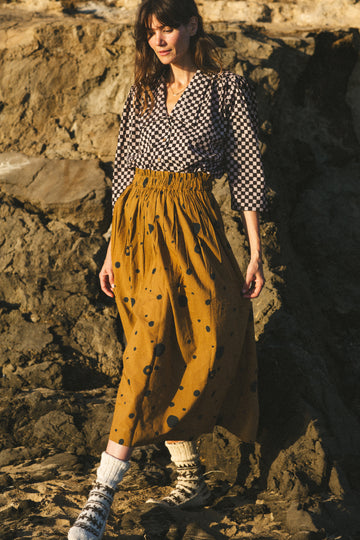 The Circles All Over Skirt features a striking brown and navy block print with circular patterns. Made from 100% handwoven cotton, it offers a comfortable mid-rise elasticated waistband and a chic mid-calf length, perfect for a polished yet relaxed style.