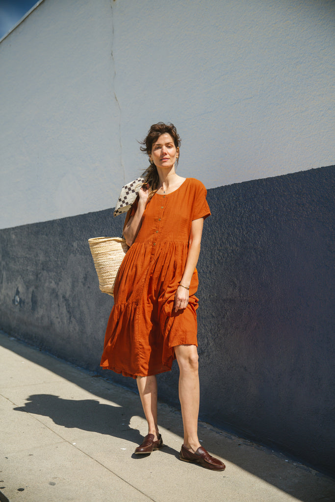 Rust orange tiered midi dress with a relaxed fit, short sleeves, a round neckline with a buttoned placket, and soft, lightweight fabric for an effortless, breezy style.