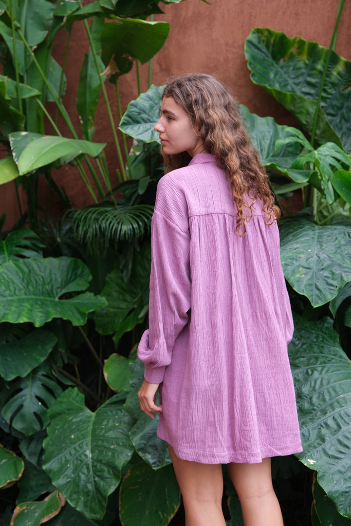 Introducing the Artist Smock, a collaboration between Audrey E Leary and World of Crow. This pink dual-tone smock is crafted from thick, handwoven organic cotton and features a straight collar, puff full sleeves, and spacious pockets. With a short length and gathered cuffs, it offers a comfortable fit and is perfect for painting, crafting, and staying cozy during travel.