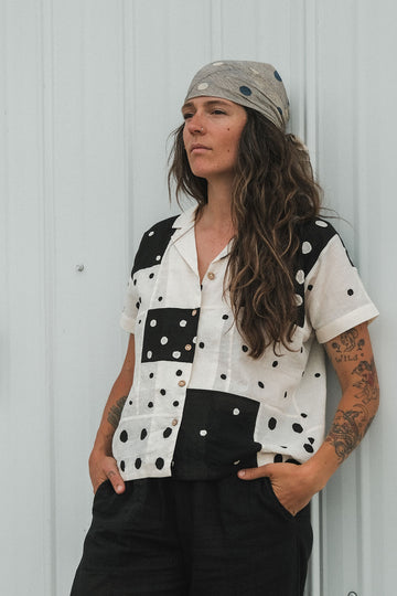 Black and white handwoven cotton patchwork top featuring short sleeves with solid white cuffs and a front button placket. Fully lined and crafted from lightweight, breathable fabric that feels soft on the skin. Ethically made using traditional techniques, with each piece offering unique variations in color and pattern. Falls 22” from the shoulder and fits true to size—perfect for effortless, everyday styling with an artisanal touch.