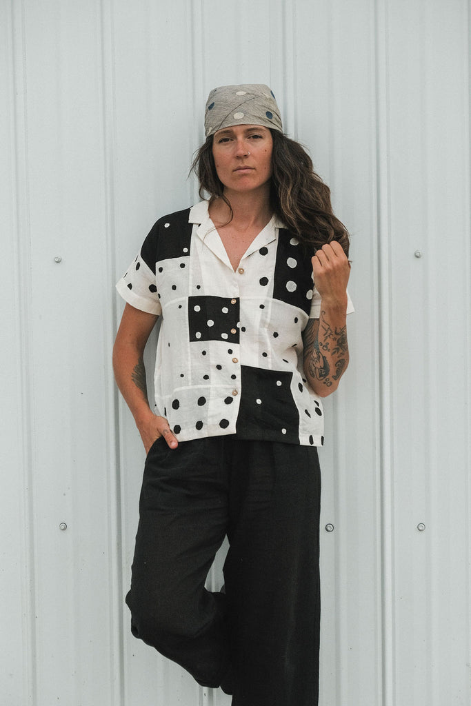 Black and white handwoven cotton patchwork top featuring short sleeves with solid white cuffs and a front button placket. Fully lined and crafted from lightweight, breathable fabric that feels soft on the skin. Ethically made using traditional techniques, with each piece offering unique variations in color and pattern. Falls 22” from the shoulder and fits true to size—perfect for effortless, everyday styling with an artisanal touch.
