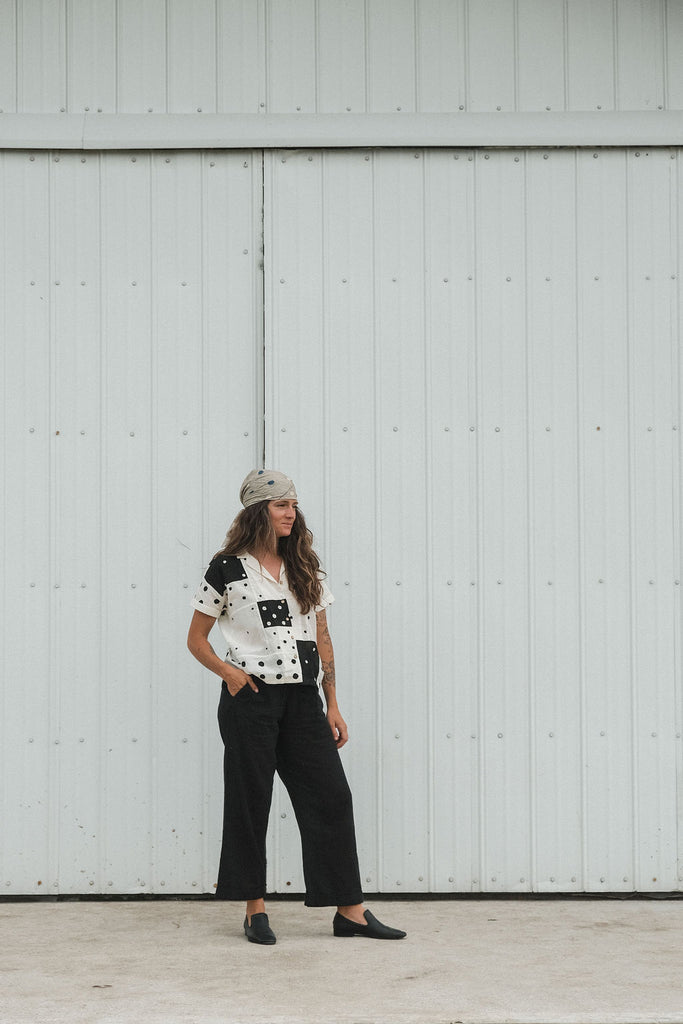 Black and white handwoven cotton patchwork top featuring short sleeves with solid white cuffs and a front button placket. Fully lined and crafted from lightweight, breathable fabric that feels soft on the skin. Ethically made using traditional techniques, with each piece offering unique variations in color and pattern. Falls 22” from the shoulder and fits true to size—perfect for effortless, everyday styling with an artisanal touch.