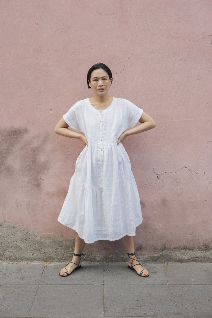 White A-line midi dress with cap sleeves, a button-down front, a gathered waist, it has delicate checks adding a texture to the garment. Made from lightweight, breathable fabric for a relaxed fit.