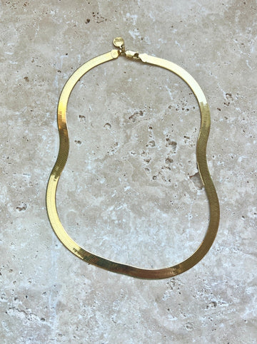 Introducing our gold herringbone necklace, a vintage-inspired statement piece made in Italy. This necklace features a striking 18" length and 7mm thickness, elegantly plated in 14k yellow gold. Its classic design and luxurious finish make it a timeless addition to any jewelry collection.