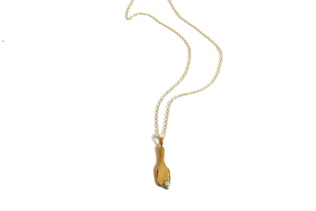 Introducing the Broken Vessel Necklace, a striking modernist design first carved in wax and cast in brass, then set with a 5mm Ethiopian Welo opal. This pendant hangs from a substantial 26" 14k gold fill chain, with the option for a customized length. Handmade in Southern California, this necklace symbolizes the beauty and light that shines through imperfections.